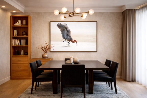 Fine art reddish egret photograph displayed above a modern dining table, capturing the bird’s graceful motion and sculptural form in an elegant interior.