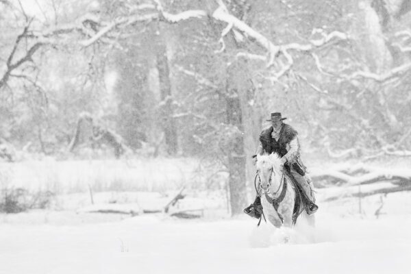 cowboy riding horse in heavy snow storm black and white fine art photography